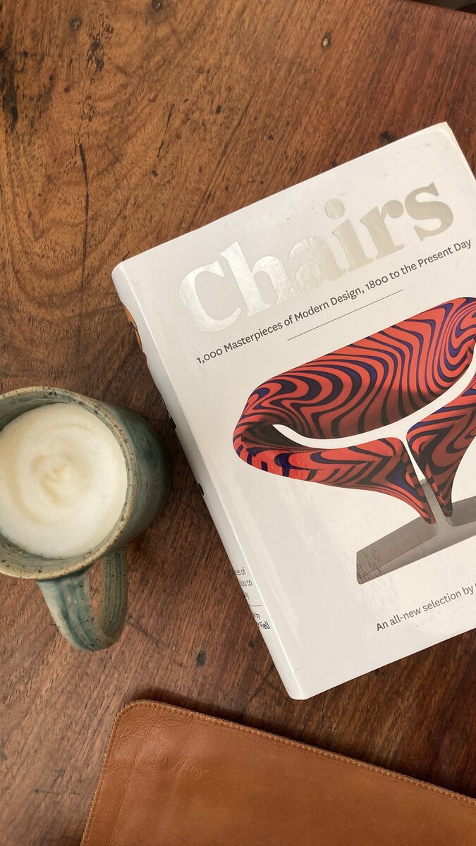 A cup set beside a book, still half full. Handmade Philippine stoneware by AWIS in everyday use.