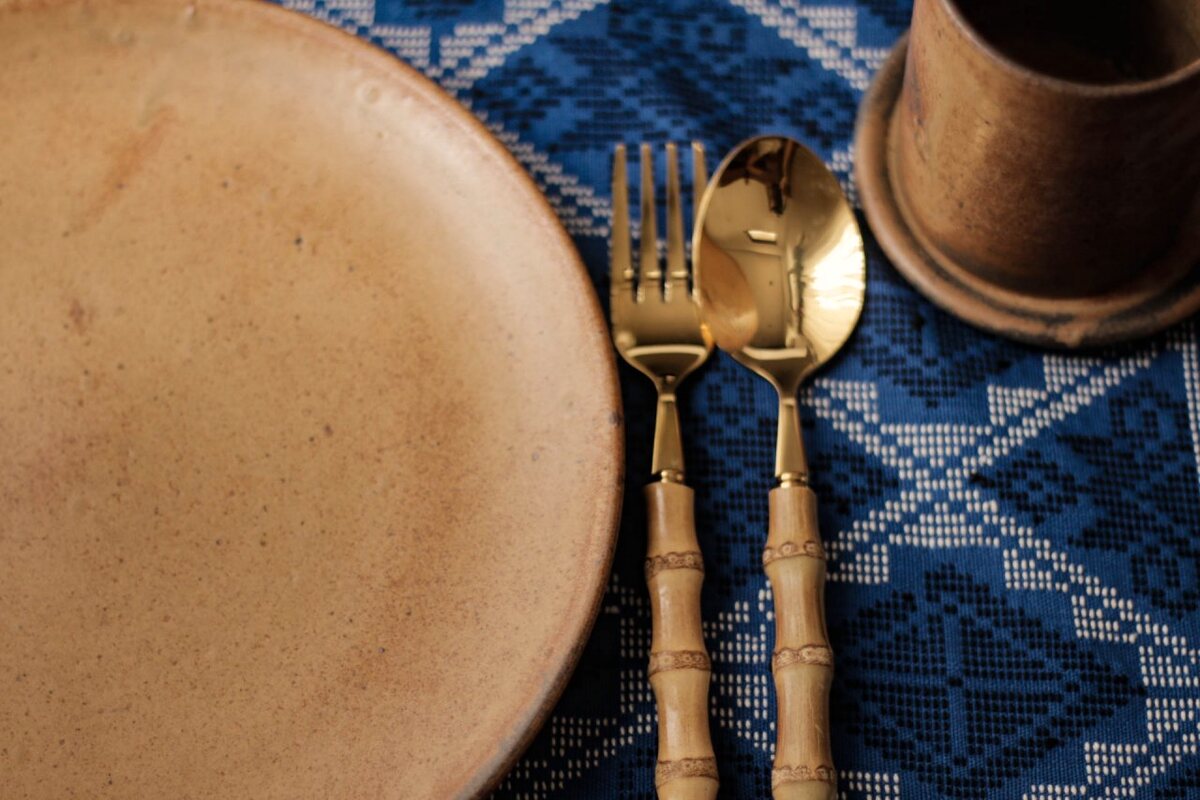 Plates and cutlery set out before anyone sits down. Handmade Philippine stoneware by AWIS in everyday use.