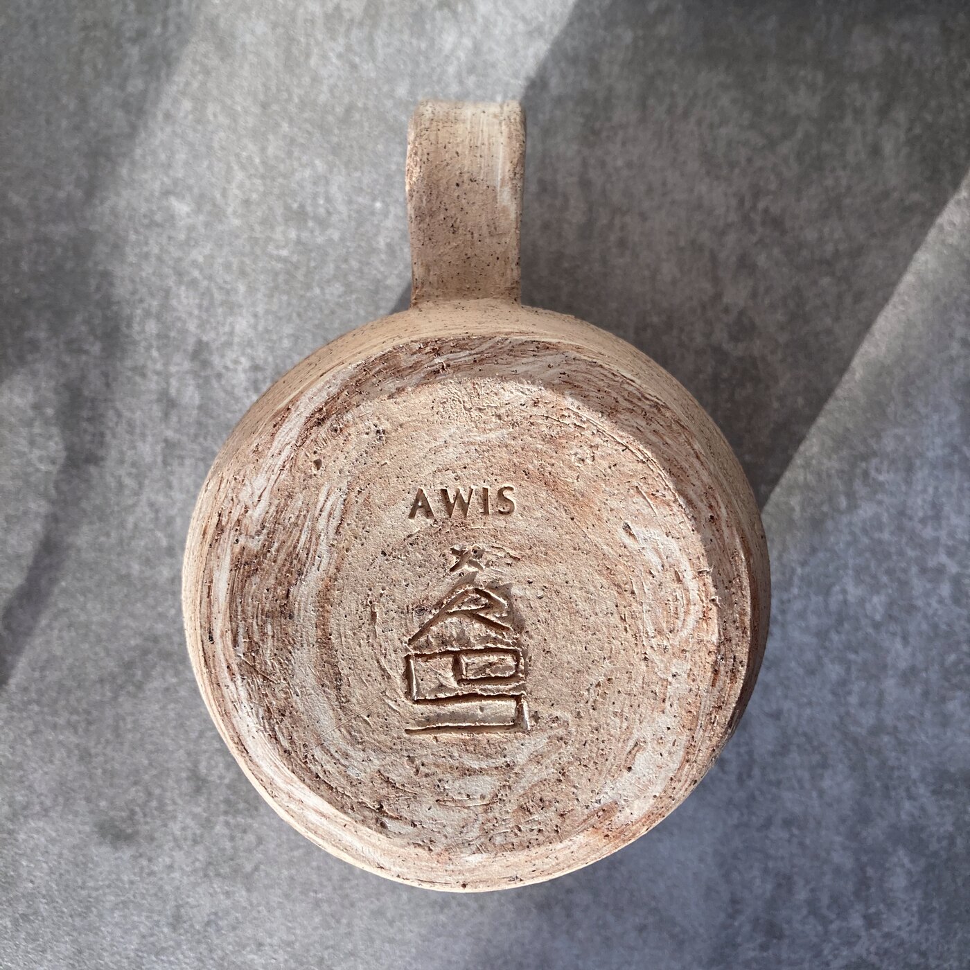 The AWIS makers stamp pressed into the unglazed base of a mug